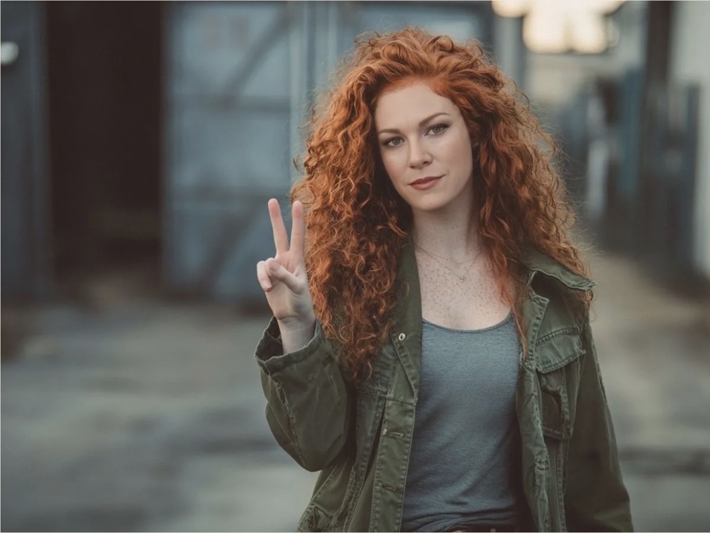 A woman with curly red hair making a peace sign showing that she is breaking up with social media